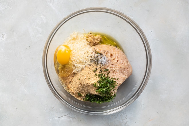 Chicken meatball ingredients in a clear bowl.