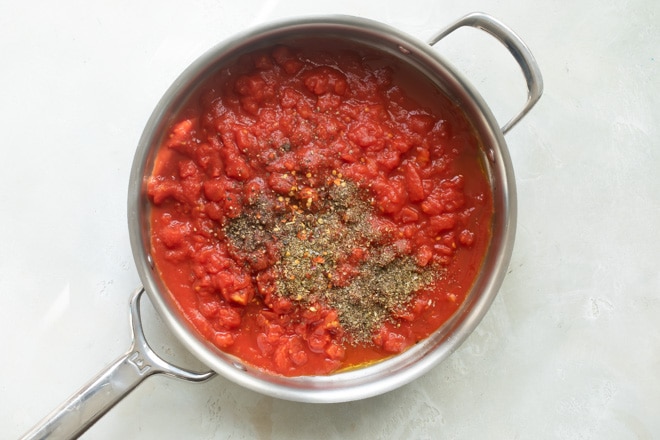 Pasta sauce and seasonings in a silver skillet.