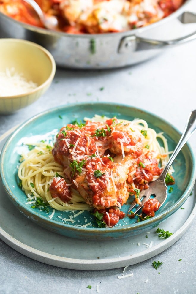 Chicken Parmesan meatball with pasta on a blue plate.