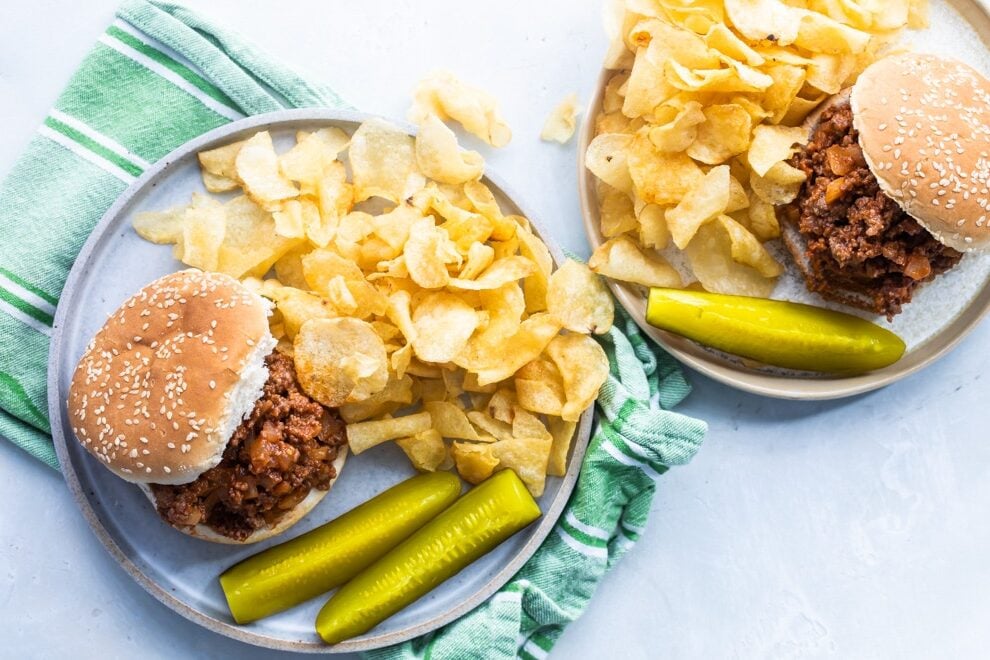 The best sloppy joes with chips and pickles on blue plates.