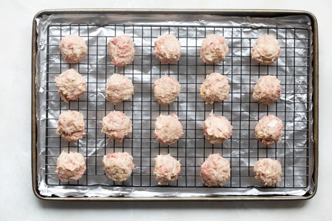 Uncooked meatballs on a baking sheet.