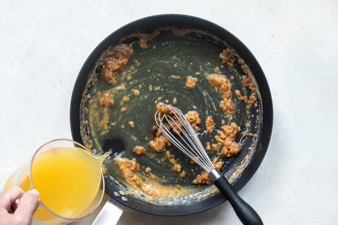 Broth being added to a black skillet.