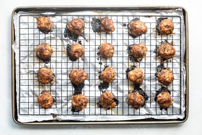 Baked meatballs on a baking sheet.