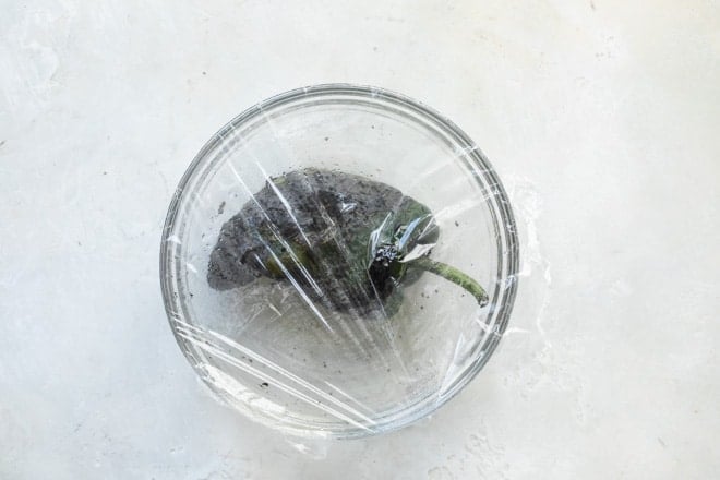 Poblano pepper covered in a bowl.
