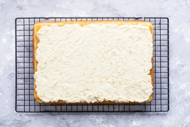Frosted Hawaiian wedding cake on a cooling rack.