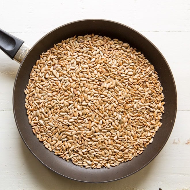 Roasted sunflower seeds in a black frying pan.