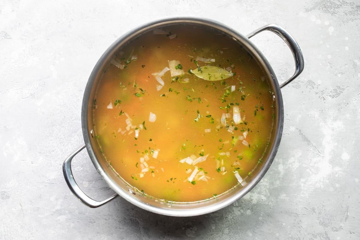 Chicken noodle soup cooking in a silver pot.