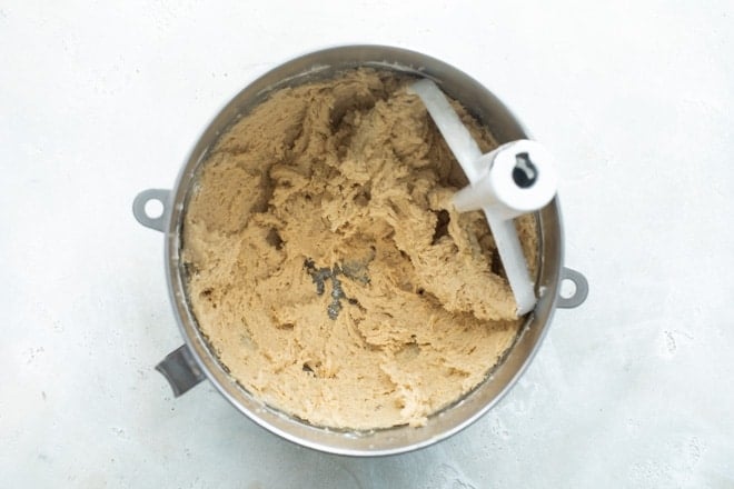 A mixing bowl with flour and other dry ingredients mixed in to the flour and sugar to make cookie dough.