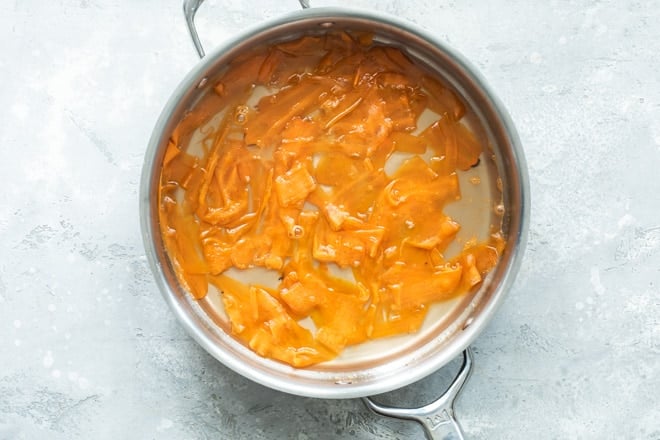 Carrot peels in water in a silver pot.