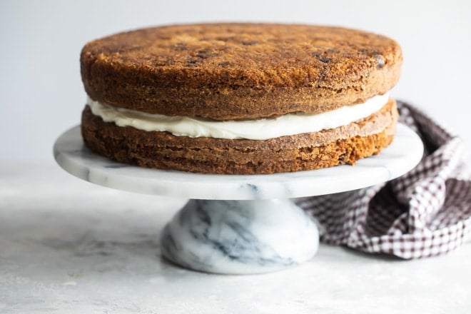 Two layers of carrot cake separated by frosting.