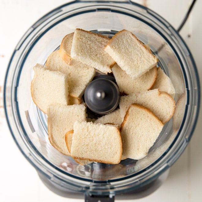 Chunks of white bread in a food processor. 