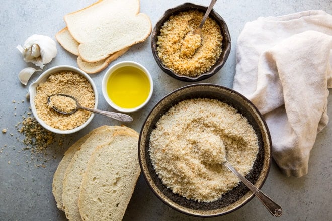 Breadcrumbs in various bowls and slices of bread.