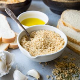 Homemade breadcrumbs in a white bowl with a spoon.
