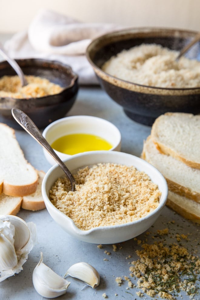Homemade breadcrumbs in a white bowl with a spoon.