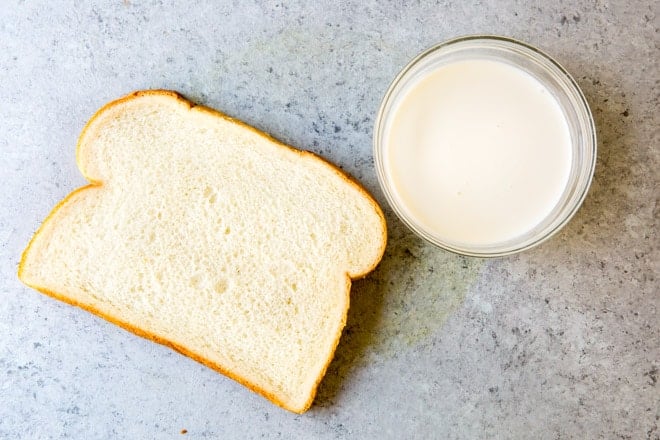 A slice of white bread and a bowl of cream.