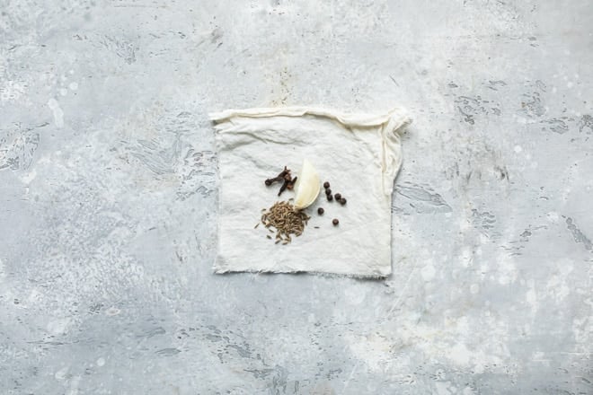 A clove of garlic, cloves, and other spices on a white towel (a sachet of spices).