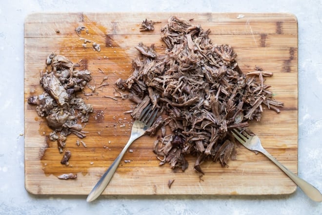 Shredded birria on a wooden cutting board.
