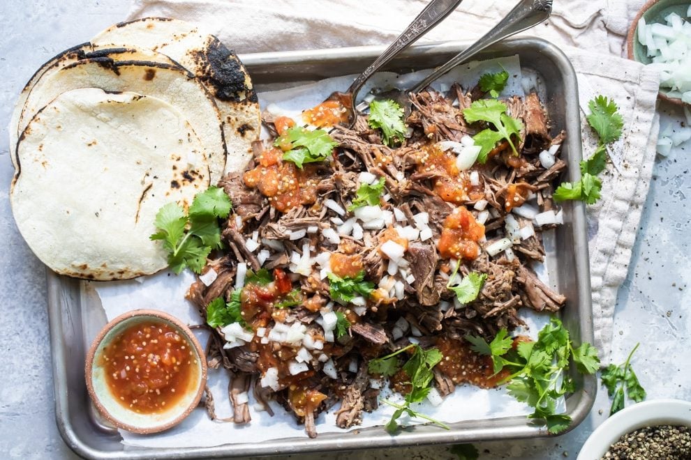 Birria on a silver platter with garnishes.