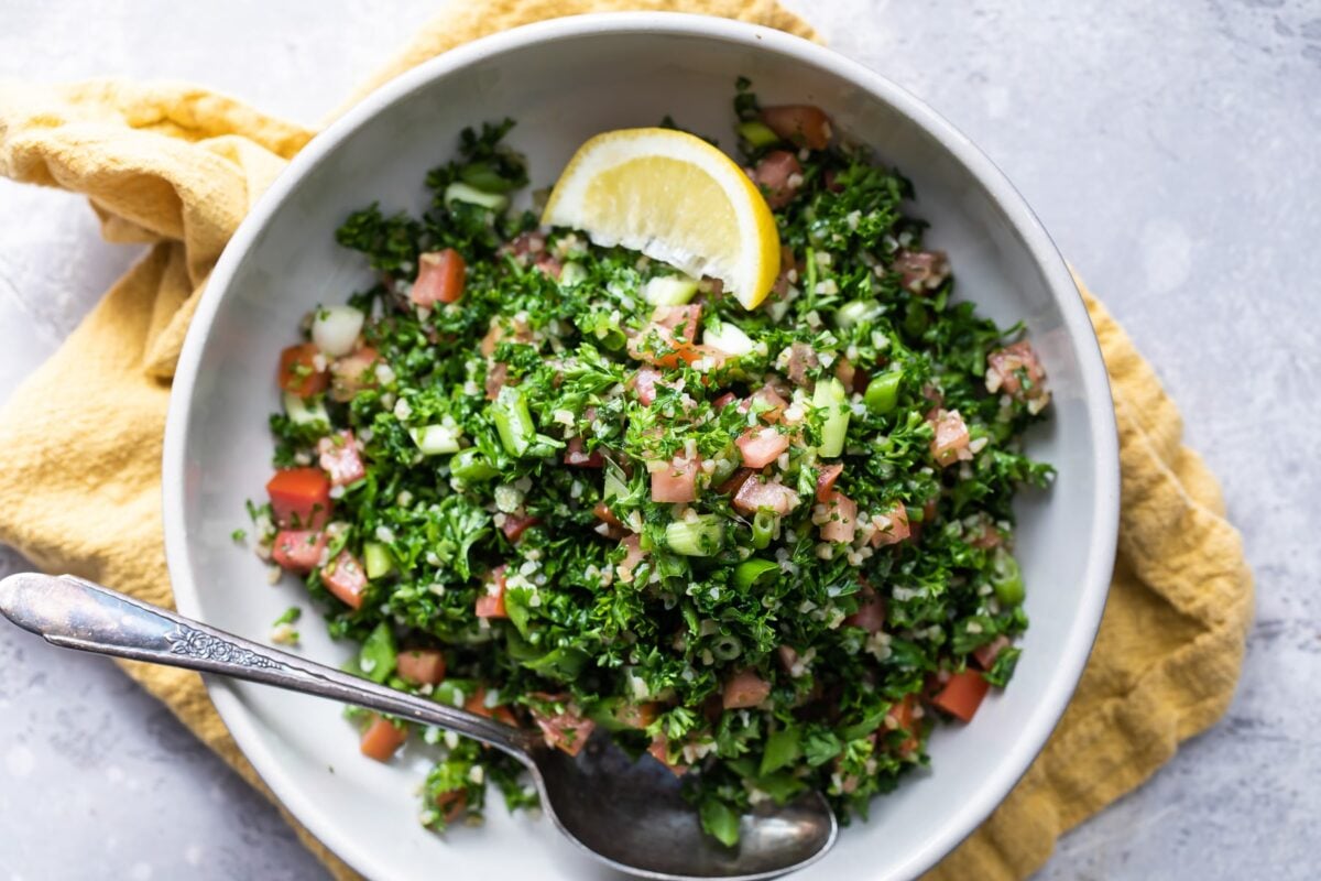 Bulgar tabbouleh in a white bowl with a lemon garnish.