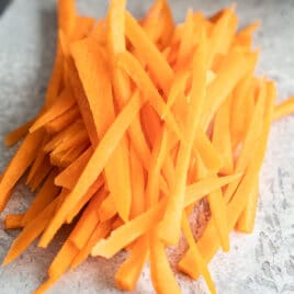 A pile of Julienned carrots on a countertop.