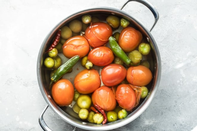 Salsa de Birrio ingredients boiling in a silver stock pot.
