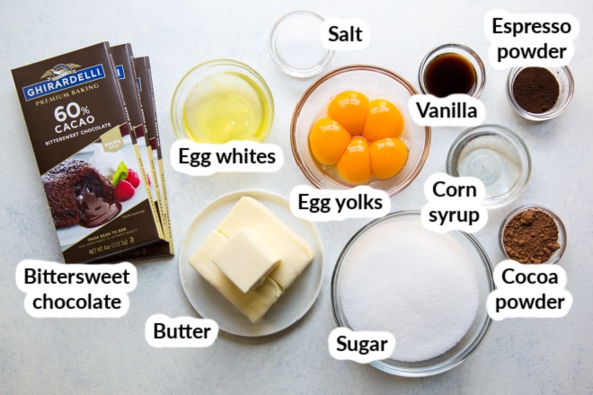 Labeled flourless chocolate cake ingredients in various bowls.