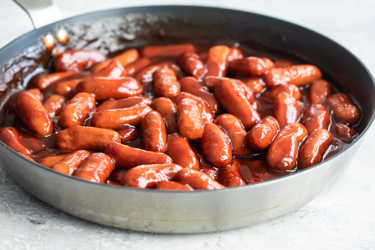 Barbecue little smokies being cooked in a skillet.