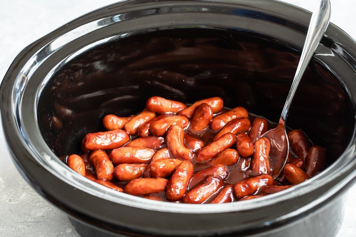 Barbecue little smokies being cooked in a crockpot.