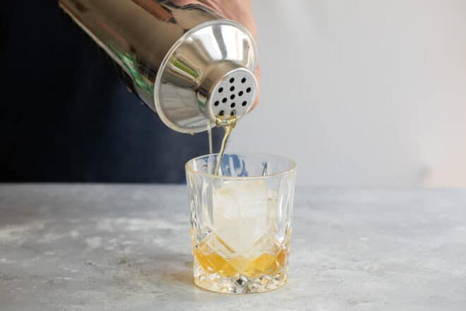 Amaretto sour being poured into a glass.