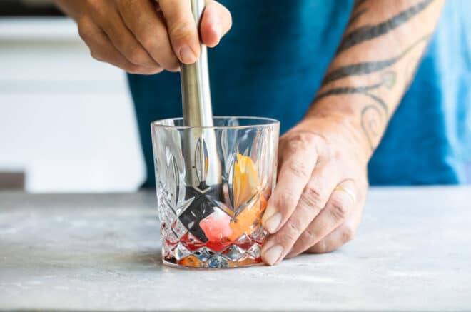 Old fashioned ingredients being muddled in a clear glass.
