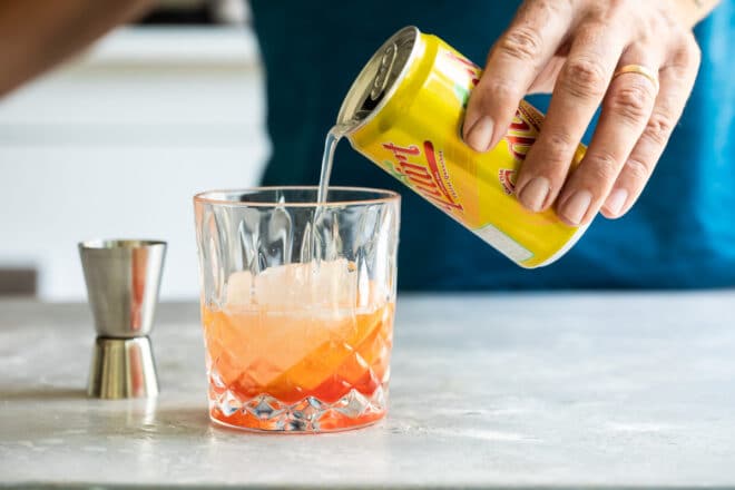 Soda being poured into a Brandy Old Fashioned cocktail.