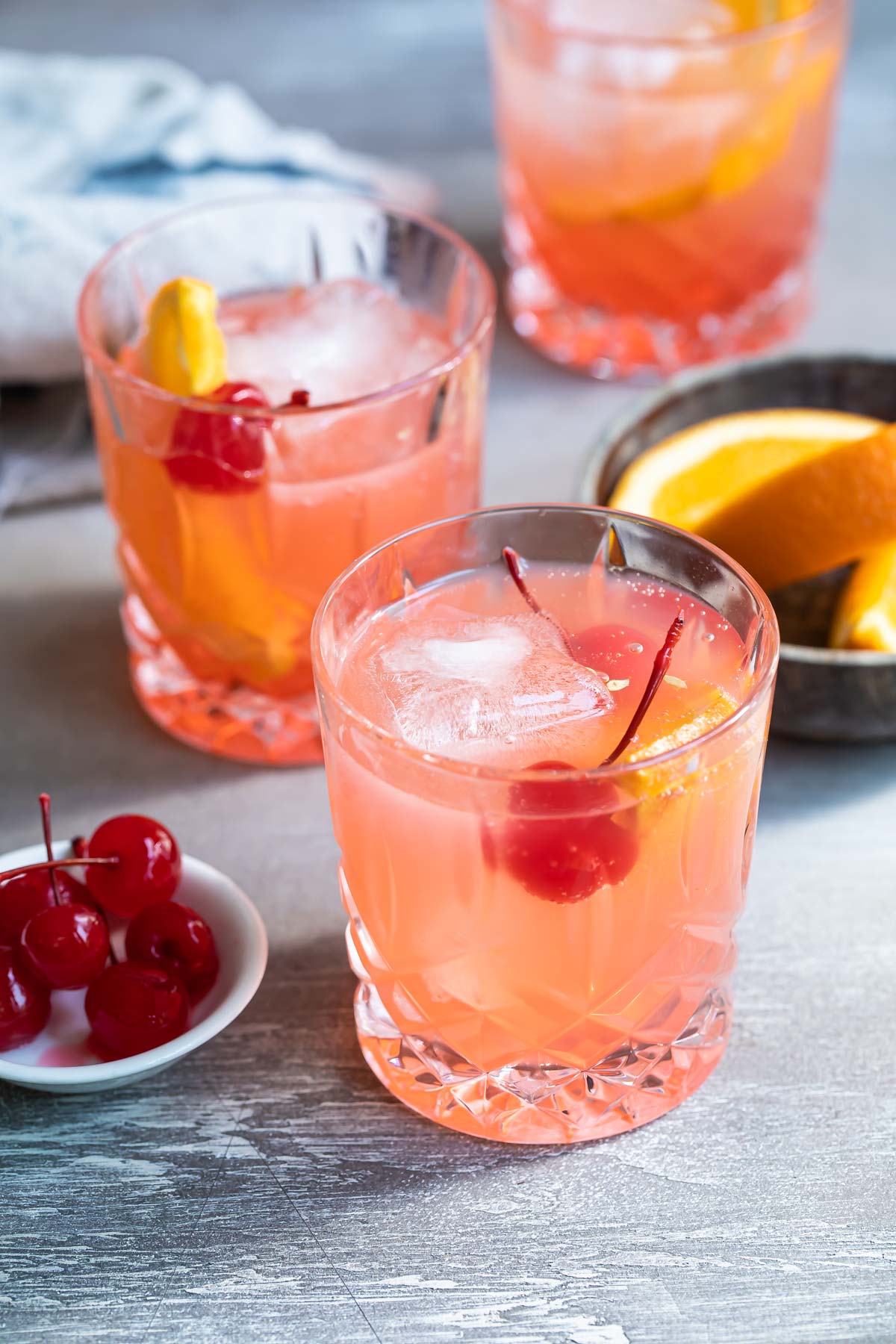 Three brandy old fashioneds in clear glasses.