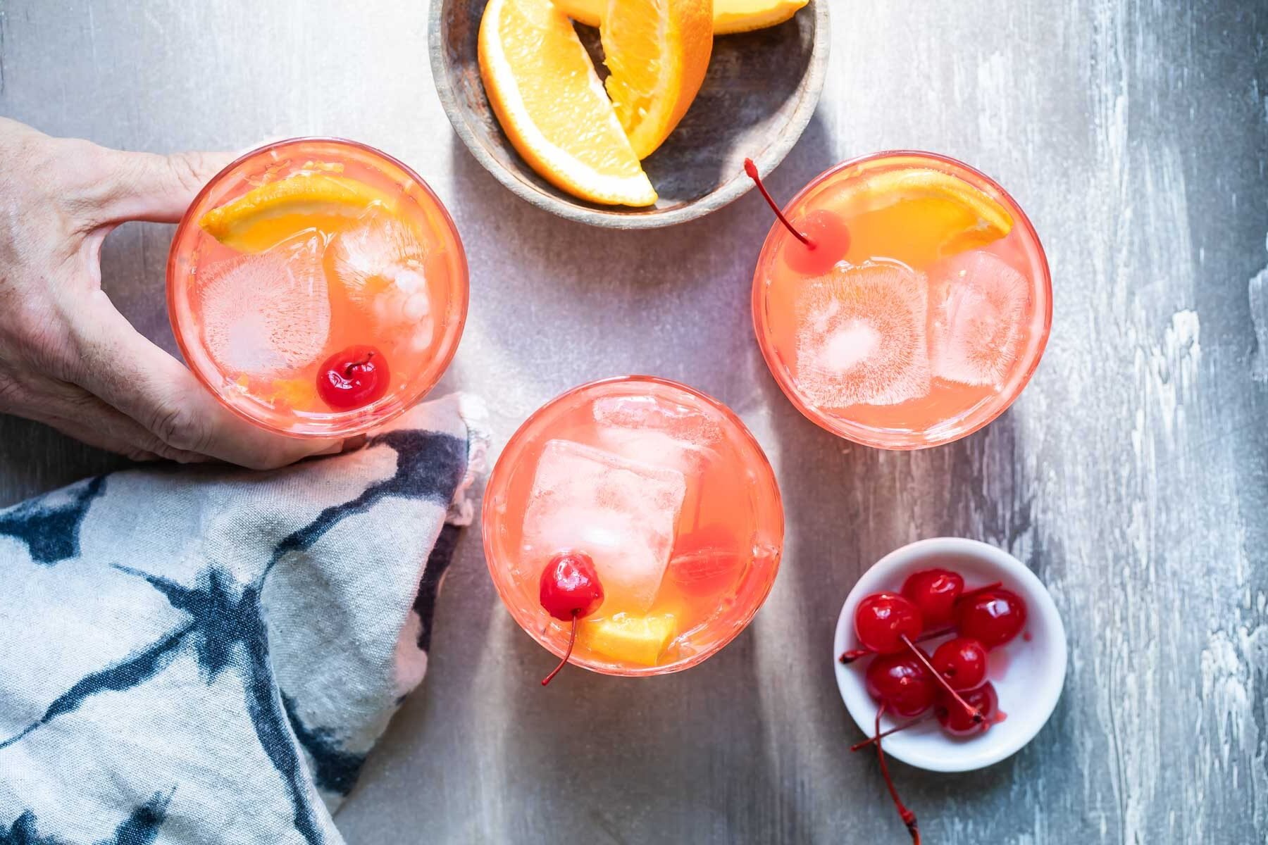 Three brandy old fashioneds in clear glasses.