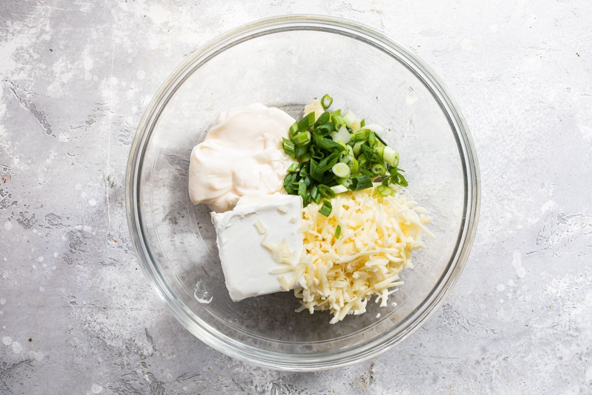 Cheesy bacon dip ingredients in a clear bowl.