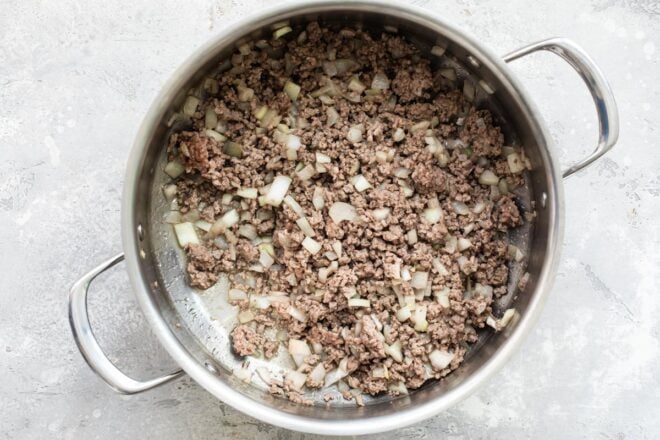 Ground beef and onions in a Dutch oven.
