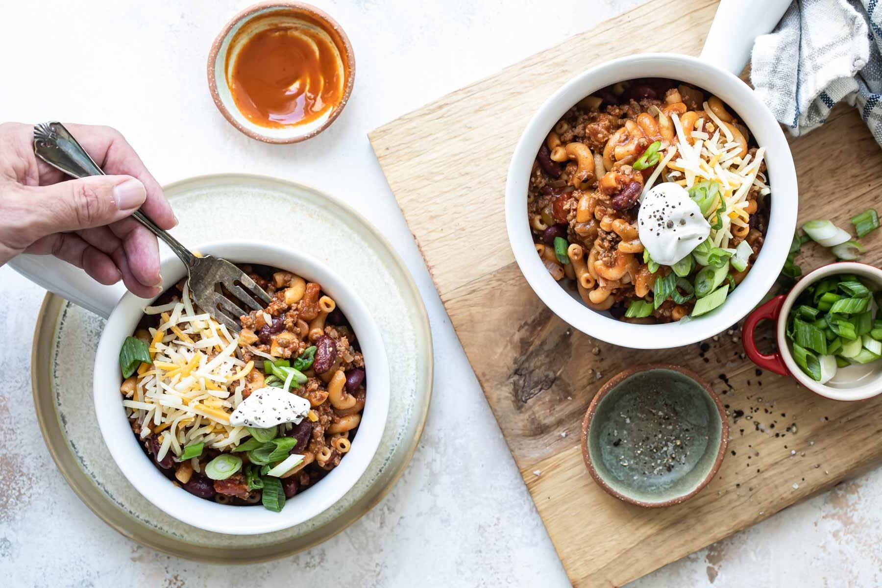 Two bowls of garnished chili mac.