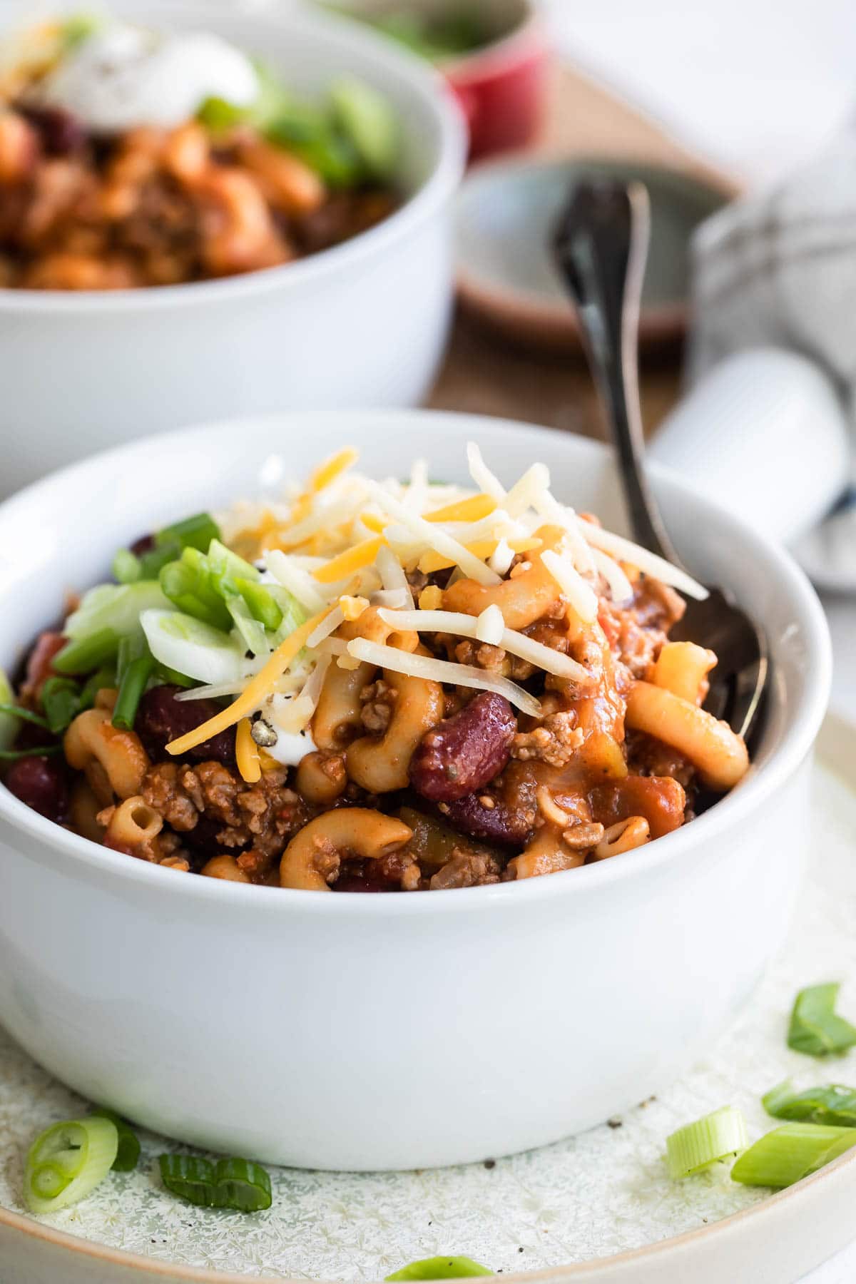 Garnished chili mac in a white handled bowl.