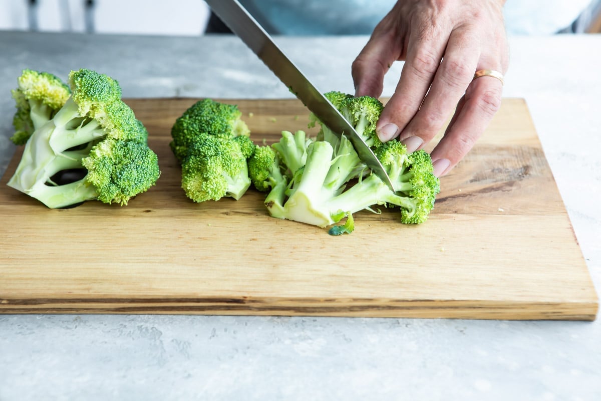 Cutting florets off a stalk of broccoli.