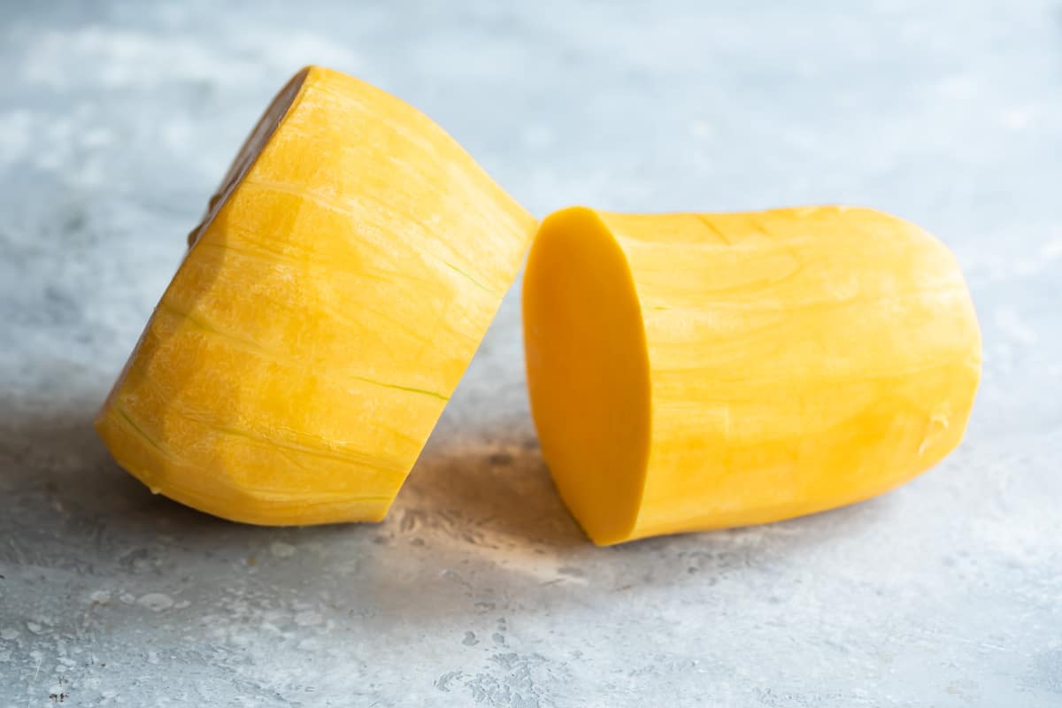 Peeled butternut squash being cut in half.