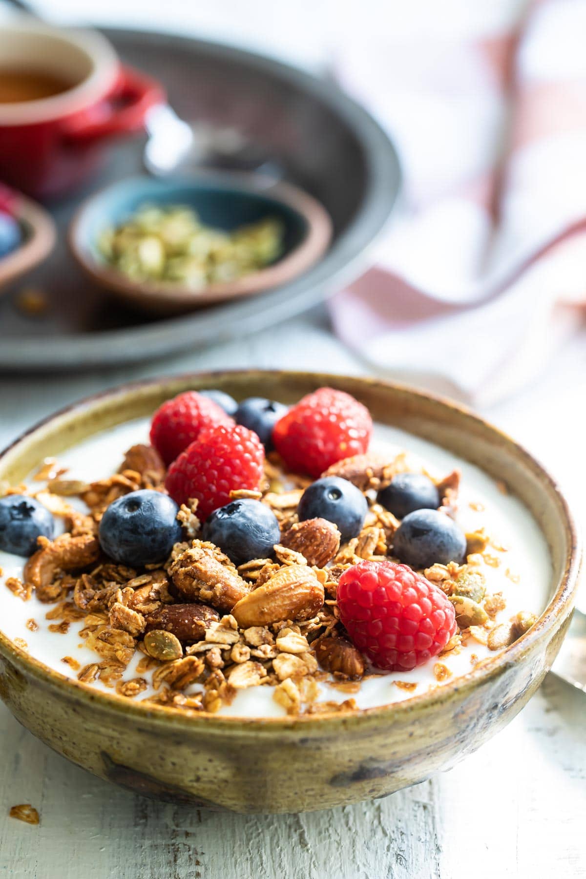 Granola and berries on top of a bowl of yogurt.