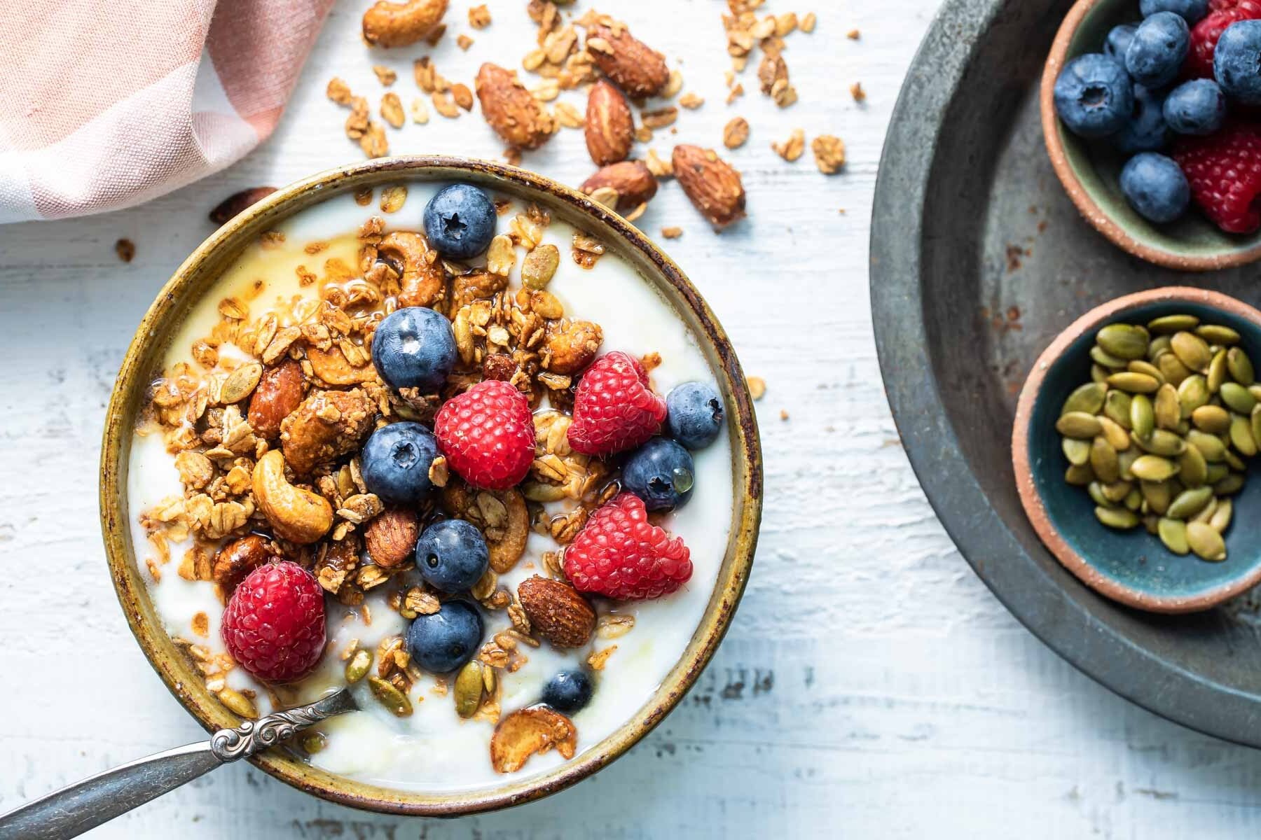 Granola and berries topping a bowl of yogurt.