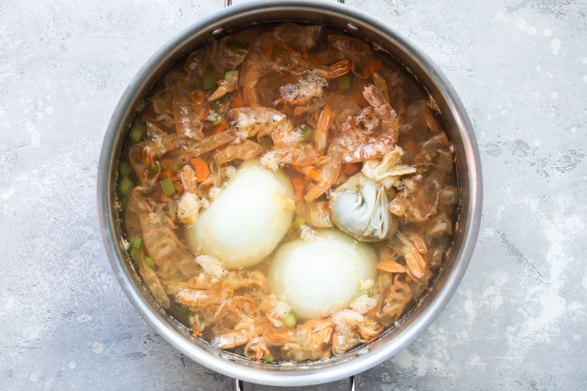 Shrimp stock ingredients in a silver pot.