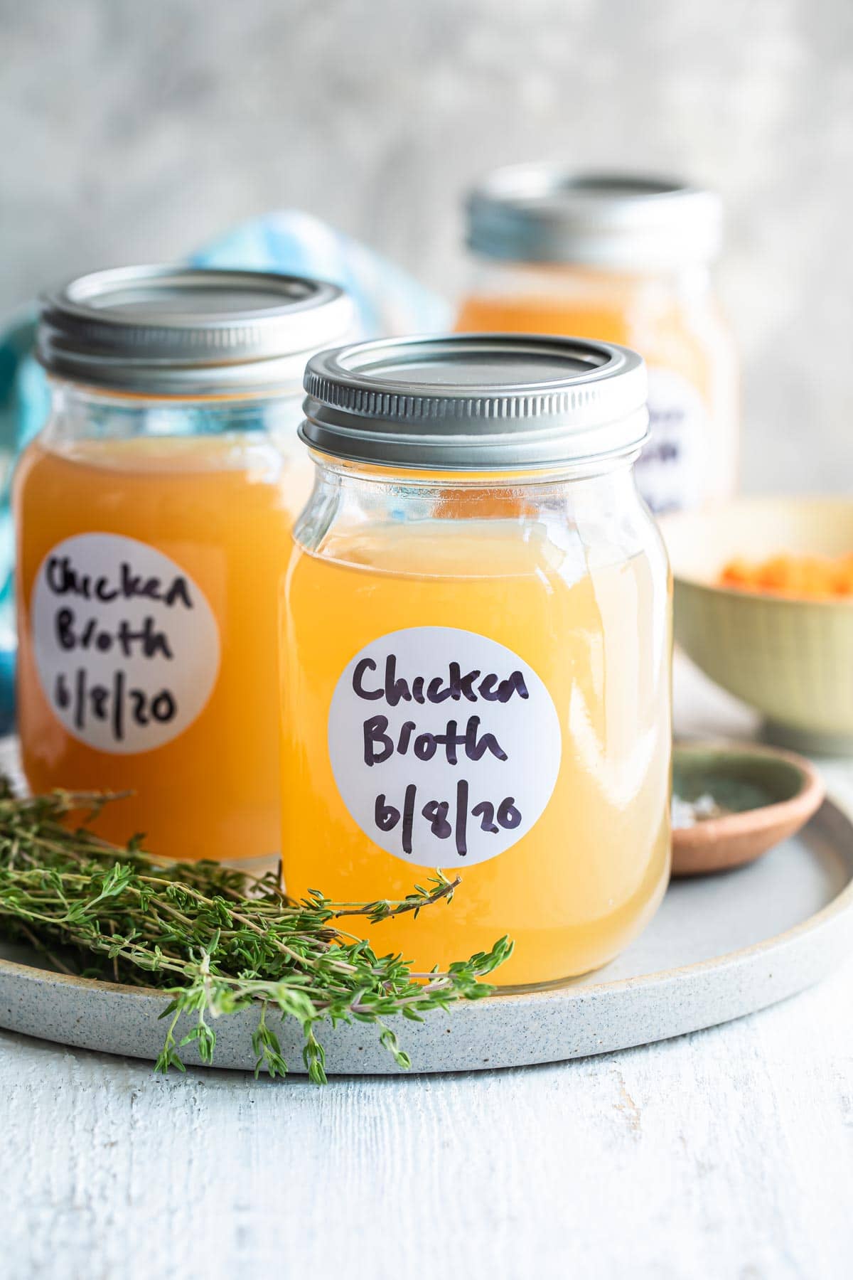 Homemade chicken broth in a jar on a plate.