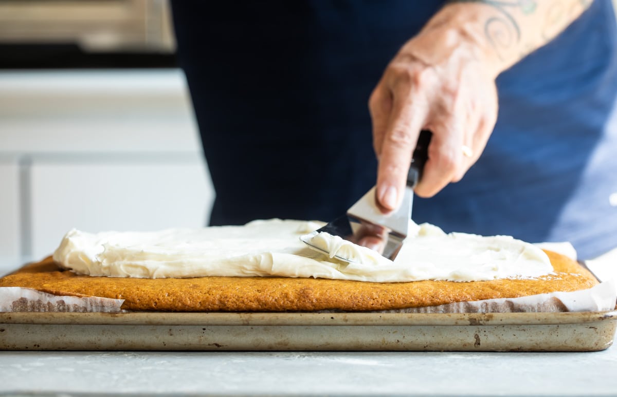Cream cheese frosting being spread on top of pumpkin bars.