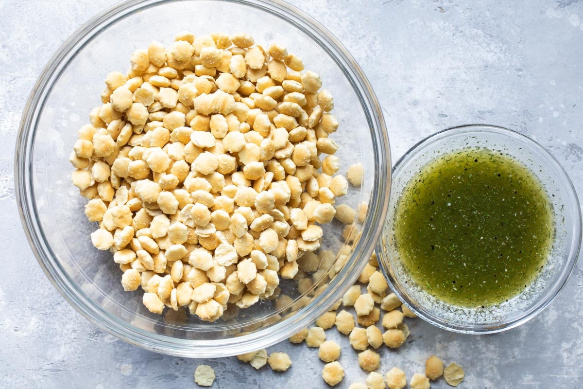 Oyster crackers in a clear bowl with a bowl of ranch liquid topping next to it.