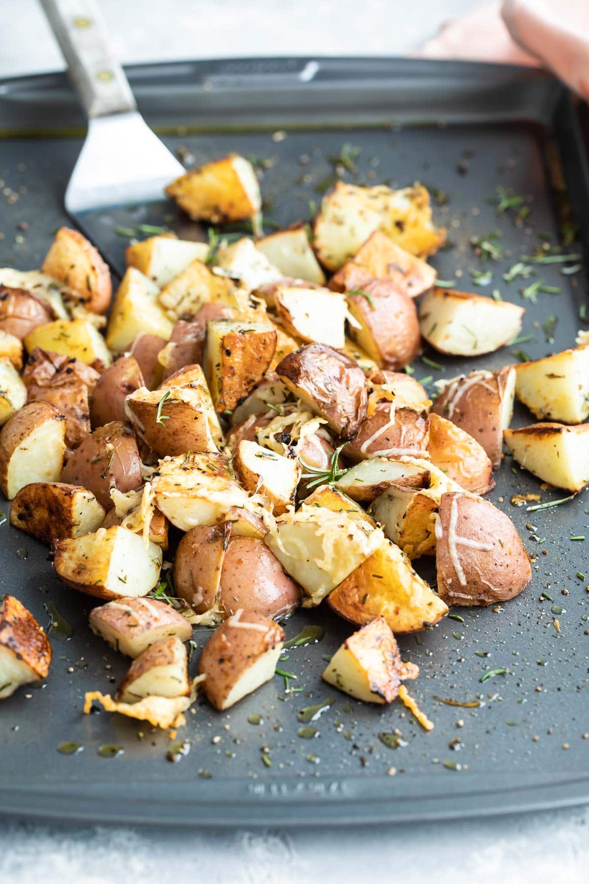 Roasted rosemary potatoes on a silver baking sheet.