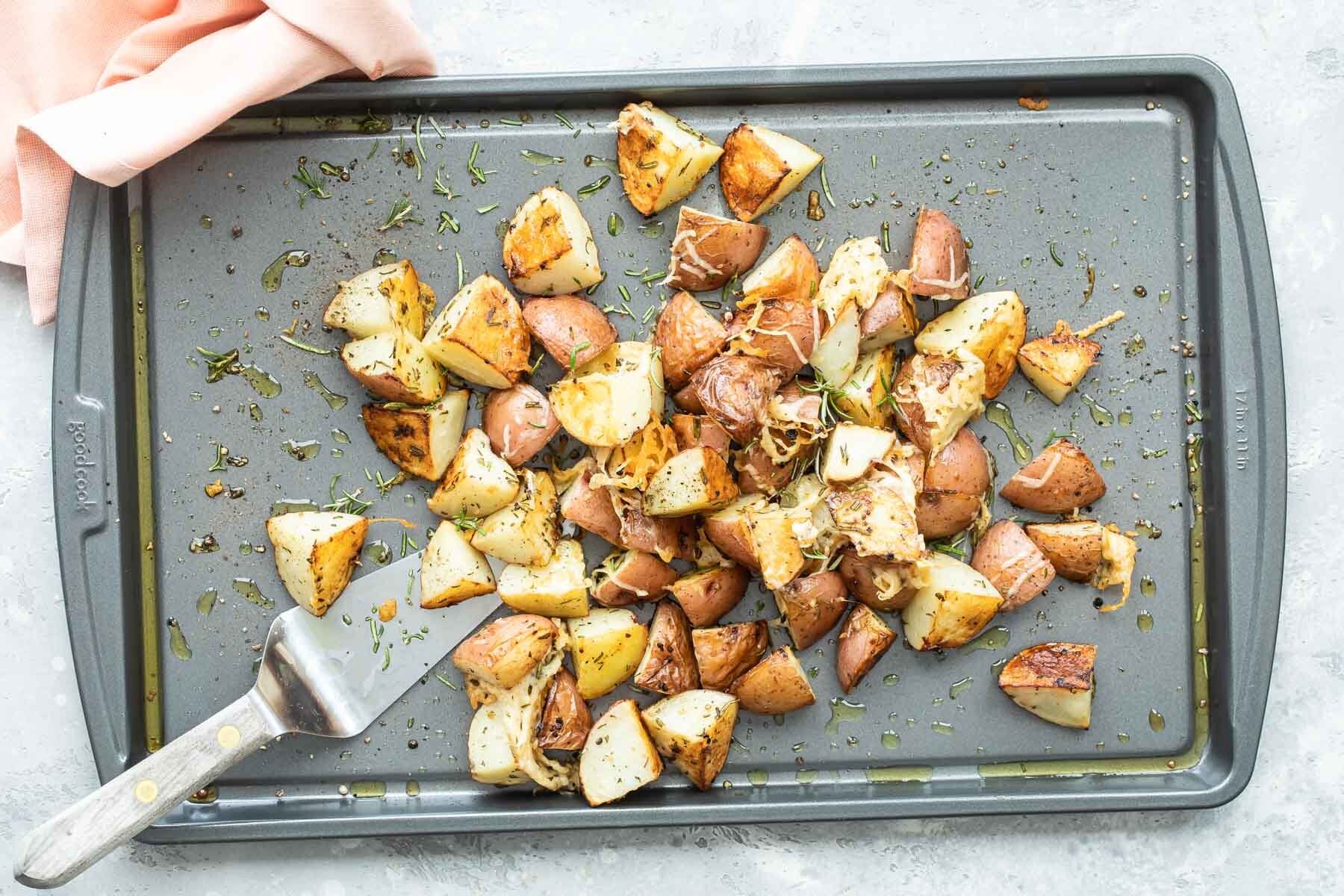 Roasted rosemary potatoes on a silver baking sheet.