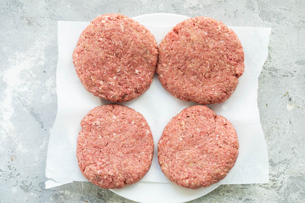 Uncooked salisbury steak patties on a plate.