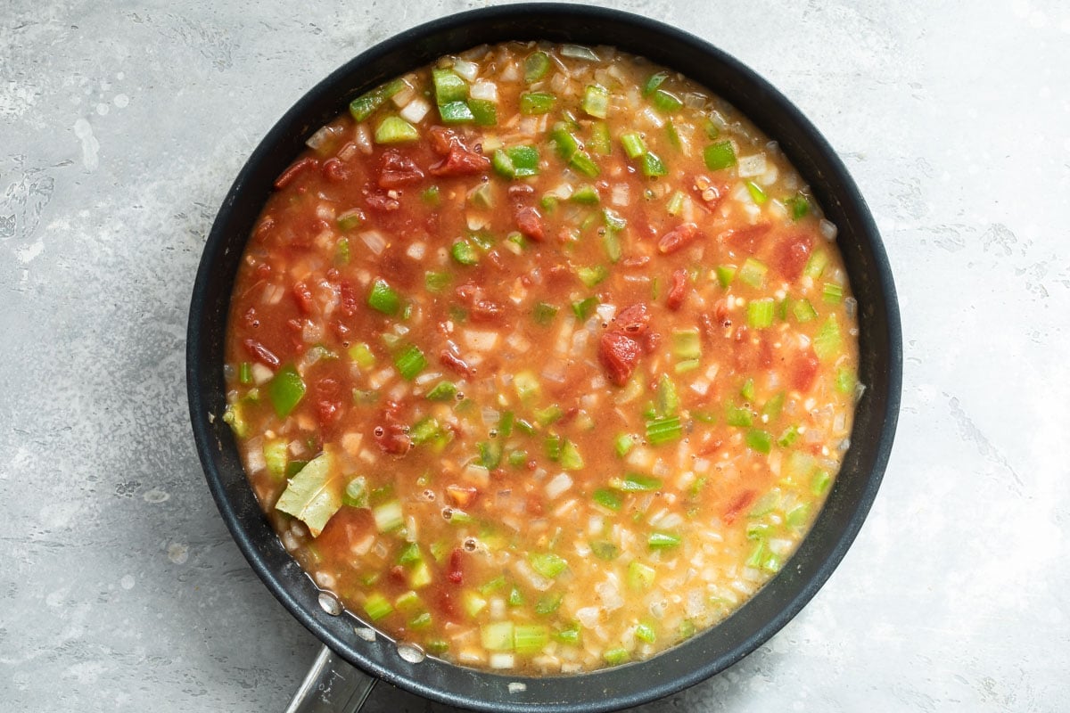 Vegetables and broth in a black skillet.