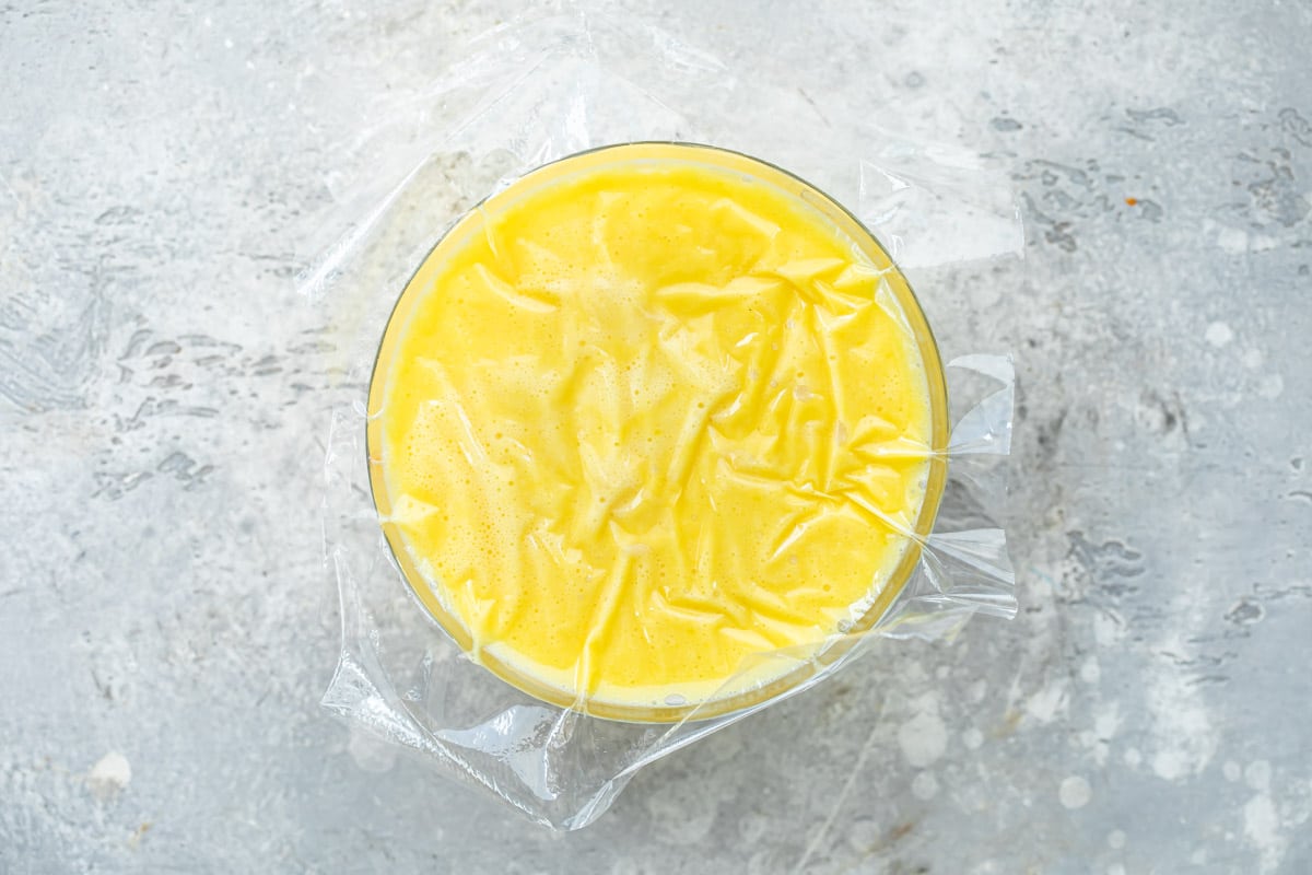 Tiramisu custard covered with plastic wrap to chill.